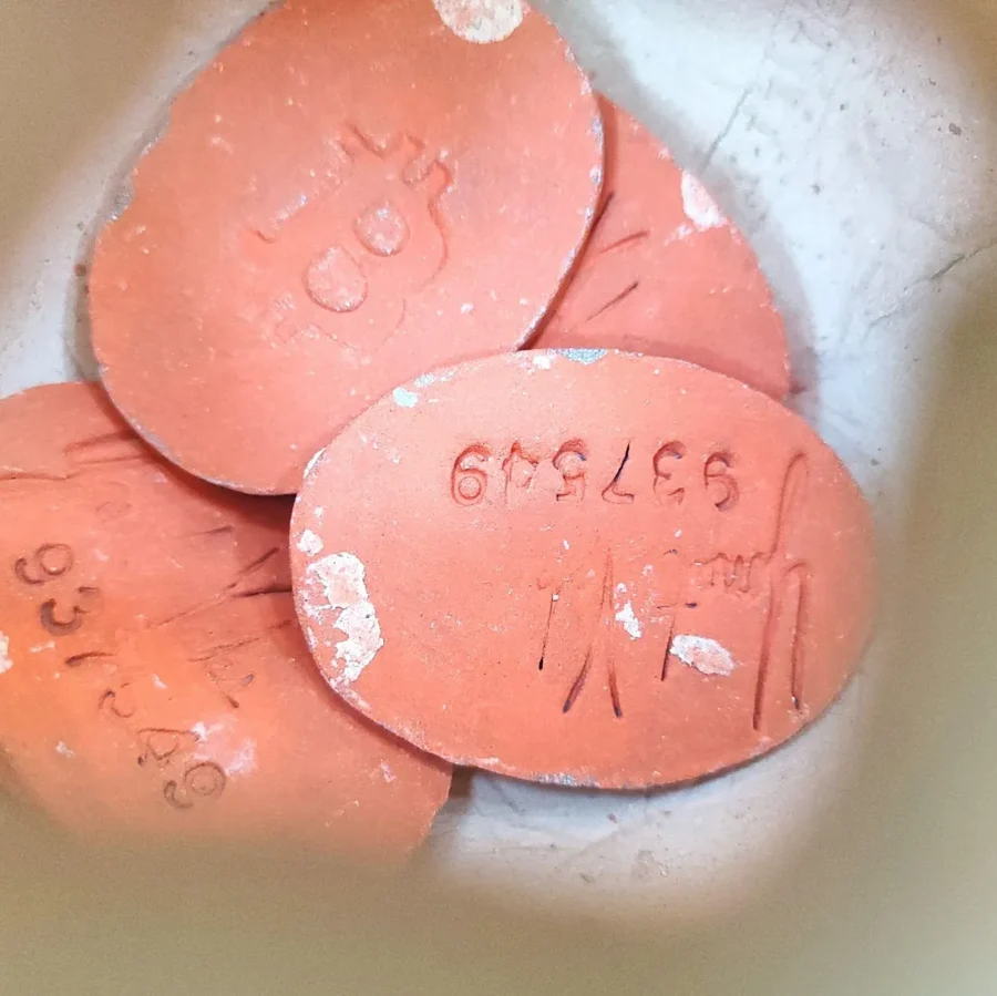 Orange clay Bitcoin tokens with block height numbers stamped in, inside a Bulla clay vessel by Yonat Vaks.