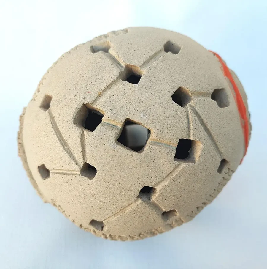 Top view of Yonat Vaks Bitcoin Bulla clay artwork showing square openings in a geometric pattern, with orange clay tokens visible inside.