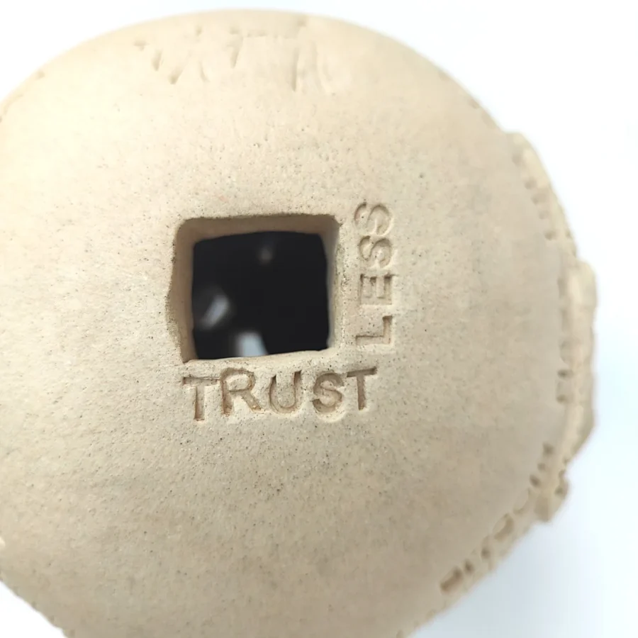 Yonat Vaks Bulla clay artwork inscribed with TRUSTLESS around the square opening, orange clay Bitcoin tokens visible inside.